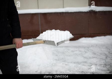 Déneigement dans la rue. Pelle pour le nettoyage des chenilles. L'homme nettoie la cour. Grande pelle. Banque D'Images
