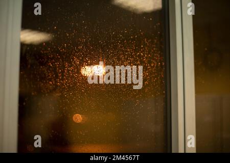 Eau sur verre. Gouttes de pluie sur la fenêtre. Fenêtre d'arrière-plan. Lumière du soir à l'extérieur de la fenêtre. Banque D'Images