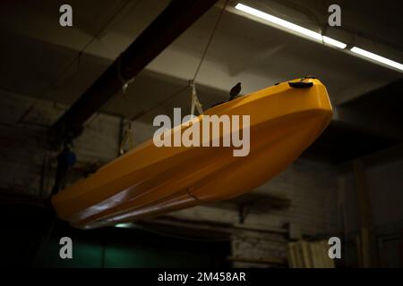 Bateau dans le garage. Le bateau est suspendu au plafond. Équipements sportifs. Transport d'eau. Véhicule. Plastique jaune. Banque D'Images