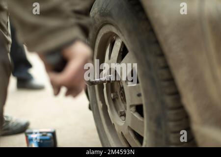 Écrou sur la roue. Levier pour remplacer la roue sur la voiture. La main tient la clé. Clé. Banque D'Images