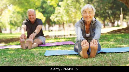 Nous avons toujours commencé chaque matin avec un étirement. un heureux couple senior faisant du yoga ensemble au parc. Banque D'Images