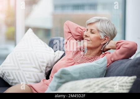 Il est temps de se détendre. gaie femme d'âge mûr décontractée et relaxante sur son canapé à la maison. Banque D'Images