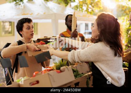 De la ferme à la porte du concept de livraison. Jeune femme transportant un sac de livraison et prenant la commande sur le marché alimentaire, livrant des produits biologiques frais sains dans une boîte de l'agriculture locale. Banque D'Images