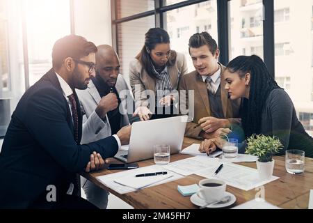 La technologie et le travail d'équipe vous permettent d'y parvenir plus rapidement. un groupe de jeunes hommes d'affaires utilisant un ordinateur portable lors d'une réunion dans un bureau moderne. Banque D'Images