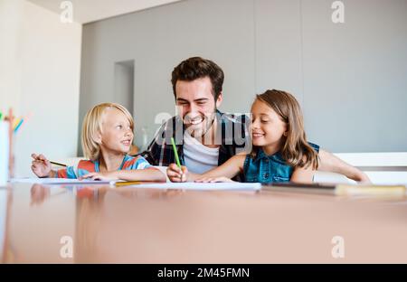 Nous avons toujours le meilleur des temps ensemble. un jeune père aidant ses deux petits enfants avec leurs devoirs à la maison. Banque D'Images