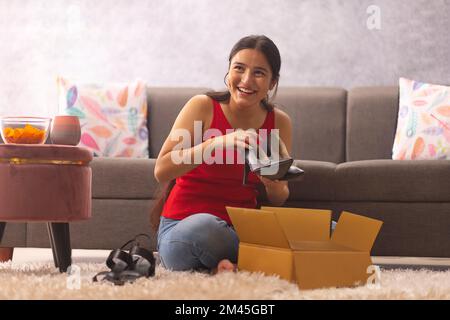 Bonne adolescente déballant des chaussures de carton après les achats en ligne Banque D'Images