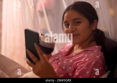 Gros plan portrait d'une adolescente utilisant un téléphone portable avec une tasse de café dans la main Banque D'Images