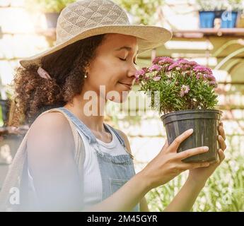 Femme noire, fleur et jardin, odeur de plante avec la nature et en plein air, jardinage et shopping à la pépinière. Croissance, floraison et fleurs avec naturel Banque D'Images