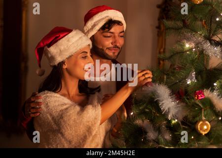Portrait d'un jeune couple heureux ensemble décorant l'arbre de Noël Banque D'Images