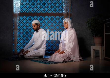 Portrait d'un couple musulman priant ensemble à la maison Banque D'Images