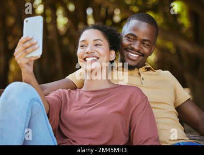 Couple noir, téléphone et selfie avec le sourire au parc naturel extérieur pour les voyages, le bonheur et la mise à jour du contenu de l'image de profil des médias sociaux. Homme heureux et Banque D'Images