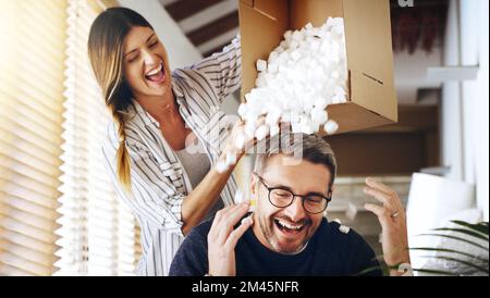 Ce n'est que l'idiot. un couple mature s'amusant avec des balles d'emballage en mousse tout en déplaçant la maison. Banque D'Images