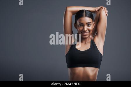 Relâchez ces muscles pour un entraînement plus détendu. Portrait studio d'une jeune femme sportive qui étire les bras sur un fond gris. Banque D'Images