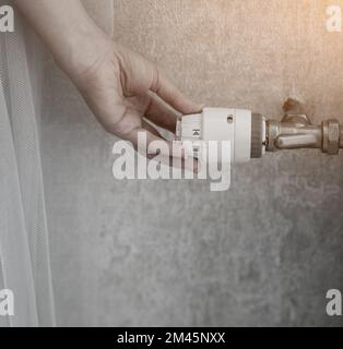 Femme réglant la température sur le radiateur de chauffage. économie et préservation de la chaleur dans la pièce Banque D'Images