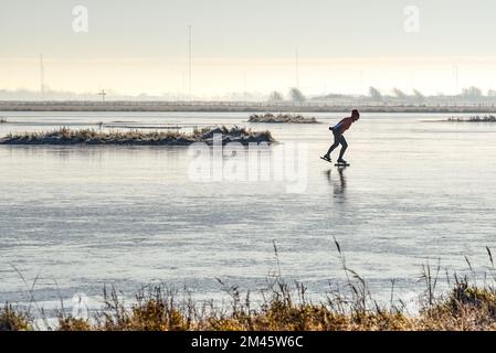 Den Helder, pays-Bas. Décembre 2022. Patineuse solitaire sur un étang gelé en paysage d'hiver en Hollande. Photo de haute qualité Banque D'Images