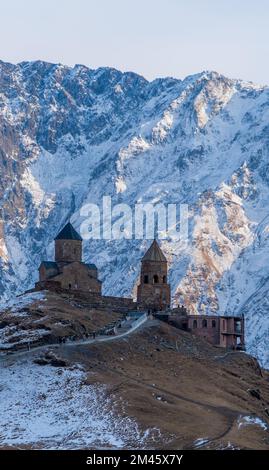 Une vue verticale de la superbe église de la Trinité de Gergeti, dans le nord de la Géorgie, avec des montagnes enneigées en arrière-plan Banque D'Images