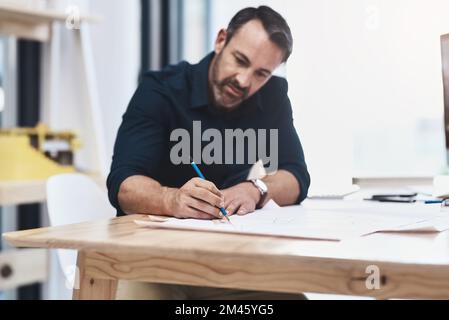 Mettre sa vision sur le papier. un architecte homme mature travaillant sur un design dans son bureau. Banque D'Images