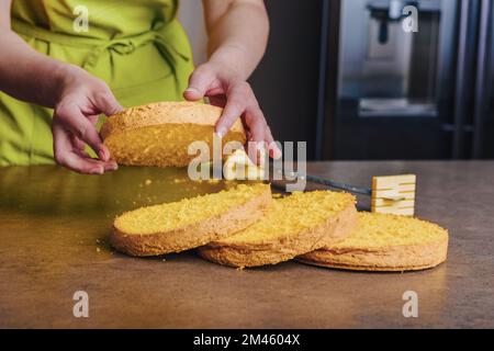 Boulanger pour femmes qui tranchent le gâteau à l'éponge traditionnel en couches à l'aide d'un couteau spécial à gâteau. Bricolage, séquence, étape par étape. Banque D'Images