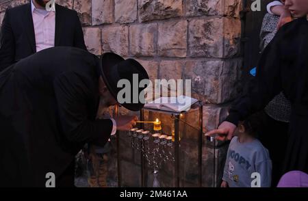 JÉRUSALEM, ISRAËL - DÉCEMBRE 18 : le rabbin Yitzchak Goldstein, chef de la Diaspora Yeshiva allume une bougie avec sa famille, à l'extérieur de leur maison la première nuit de la fête juive de Hanukkah, parfois appelée fête des lumières, sur 18 décembre 2022 à Jérusalem, Israël. Les Juifs du monde entier célèbrent aujourd'hui le premier jour de Hanukkah, le festival juif de huit jours. Hanoukkah, ou Chanukah, commémore la victoire juive en 165 avant J.-C. sur l'oppression syro-grecque menée par le roi Antiochus IV Crédit : Eddie Gerald/Alay Live News Banque D'Images