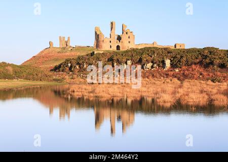 Château de Dunstanburgh vue reflétée dans un lac, près de Craster, Northumberland, England, UK Banque D'Images