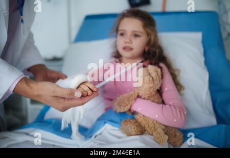 Médecin examinant la petite fille avec le bras cassé. Banque D'Images