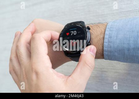 montre intelligente vérifier le pouls cardiaque, poignet homme sur fond blanc. un homme d'affaires vérifie son pouls avec une montre. Banque D'Images