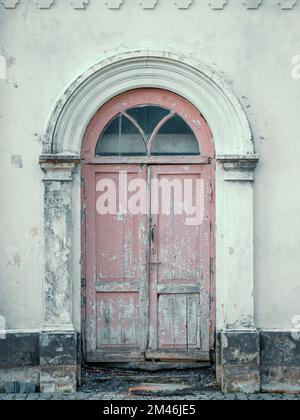 Ancienne porte d'entrée peinte en bois forme d'arche dans l'ancien mur du bâtiment. Banque D'Images