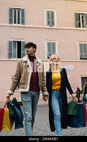 Portrait vertical d'un couple marchant avec des sacs de shopping tout en faisant du shopping au centre de la ville Banque D'Images