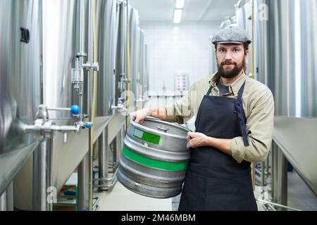 Portrait de l'ouvrier de fabrication de bière tenant le fût et regardant la caméra Banque D'Images