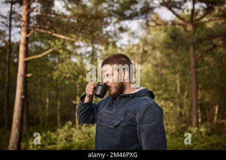 Man drinking coffee in forest Banque D'Images