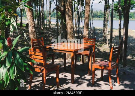 Tables et chaises en bois dans un beau jardin vert. Ensemble de meubles de tables et de chaises pour la vie extérieure. Banque D'Images