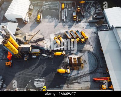 Vue aérienne du site de la société en béton avec des camions jaunes et d'autres machines lourdes garées sur le terrain Banque D'Images