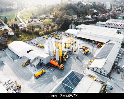 Vue aérienne de la société de construction avec beaucoup de camion jaune et de machinerie lourde garée sur le terrain Banque D'Images