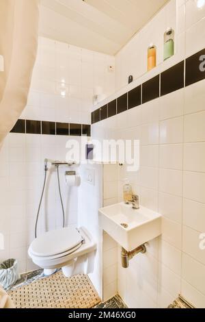 salle de bains avec carrelage noir et blanc sur les murs, le sol et les toilettes dans son coin Banque D'Images