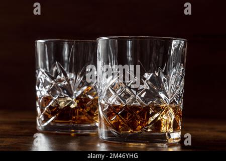 Whisky dans des verres avec glace. Whisky Bourbon sur des rochers sur fond sombre, boissons élégantes Banque D'Images
