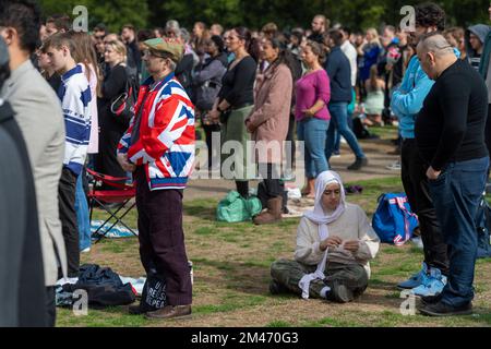 Un homme de deuil portant une veste Union Jack, à Hyde Park, regardant la diffusion en direct des funérailles de sa Majesté la reine Elizabeth II qui se déroule à Wes Banque D'Images