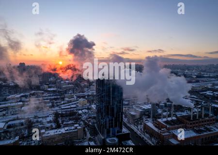 De la fumée s'échappe du tuyau de la chaudière. Système de chauffage central des immeubles d'appartements. Coucher de soleil en hiver Banque D'Images