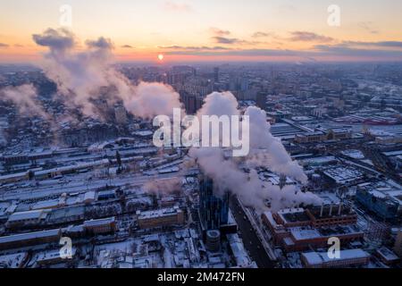 De la fumée s'échappe du tuyau de la chaudière. Système de chauffage central des immeubles d'appartements. Coucher de soleil en hiver Banque D'Images