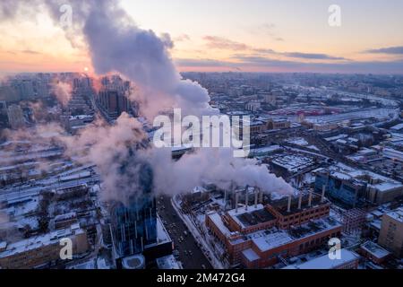 De la fumée s'échappe du tuyau de la chaudière. Système de chauffage central des immeubles d'appartements. Coucher de soleil en hiver Banque D'Images