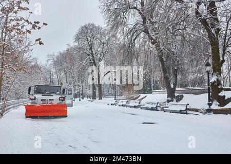 Le tracteur déneigement nettoie les allées du parc. Tracteur déneigement, saupoudrer de sel et de sable pour éviter de glisser. Service municipal de nettoyage de trottoir de Banque D'Images