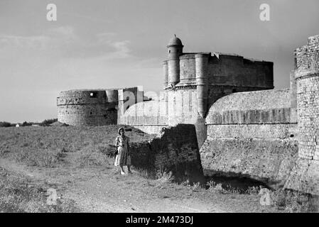 Jeune 1950s femme pose touristique devant le Moat et remparts du fort ou de la forteresse de Salses-le-Château 1951 Banque D'Images