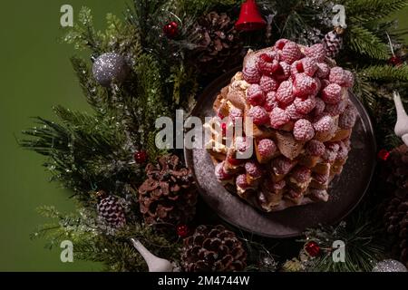 Framboise de Noël décorée de pandoro (pan d'oro) sucré italien, saupoudré de sucre glace sur fond vert Banque D'Images