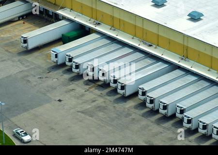 Vue de dessus du centre logistique géant avec de nombreux camions de remorques commerciales qui déchargent et chargent des produits de vente au détail pour une expédition ultérieure. Économie mondiale Banque D'Images