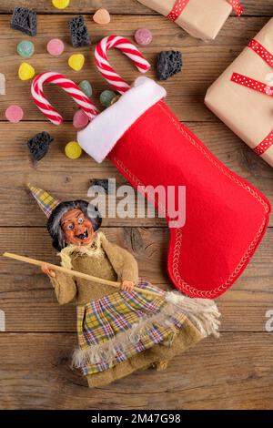 La sorcière Befana et le stockage rouge avec du charbon doux et des bonbons sur fond de bois rustique. Tradition italienne d'Epiphanie Banque D'Images