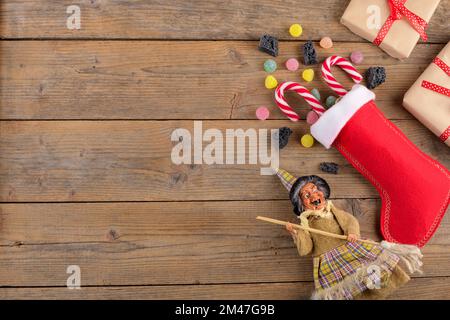 La sorcière Befana et le stockage rouge avec du charbon doux et des bonbons sur fond de bois rustique. Tradition italienne d'Epiphanie Banque D'Images