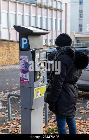 Femme payant à un système de parking payant avec panneau solaire dans la ville de Lyon, France Banque D'Images