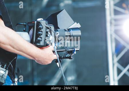 L'opérateur équipé d'une caméra vidéo enregistre un concert. Tournage de vidéos lors de l'événement... Banque D'Images