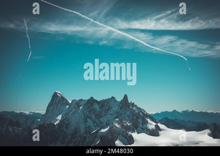 Photo aérienne d'une montagne rocheuse couverte de neige sous le ciel et de sentiers d'avion Banque D'Images