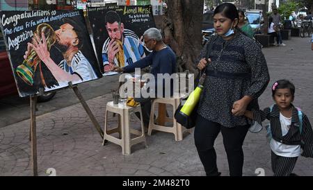 Mumbai, Inde. 19th décembre 2022. Une femme et un enfant marchant par un artiste de l'école d'art de Gurukul mettant la touche finale à un tableau de Lionel Messi embrassant le trophée de la coupe du monde, le tableau est une félicitations à l'Argentine pour avoir gagné la coupe du monde de football. L'Argentine a remporté la coupe du monde de la FIFA (Fédération internationale de football Association) après 36 ans de leur dernier triomphe sur l'Allemagne de l'Ouest en 1986. (Photo par Ashish Vaishnav/SOPA Images/Sipa USA) crédit: SIPA USA/Alay Live News Banque D'Images