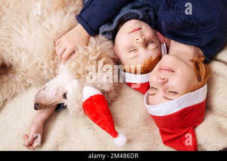 Fils avec mère et chien sont embrassant tout en étant allongé sur le canapé en nouvel an, noël. Banque D'Images